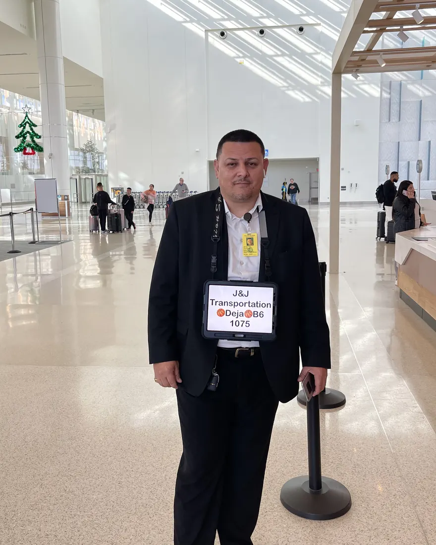 A J&J chauffeur waiting with a personalized welcome sign at Orlando International Airport