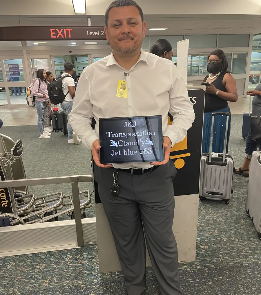 Chauffeur greeting an arriving guest with a J&J Transportation welcome sign at Orlando International Airport