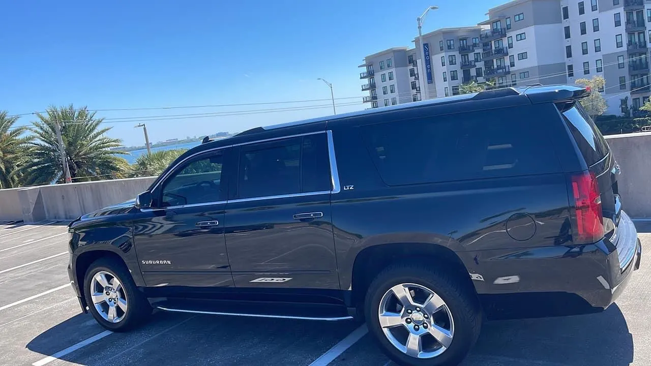Black Suburban profile against palm trees and the water