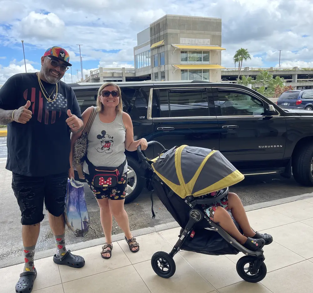 Happy family arriving at Orlando International Airport beside the black Suburban